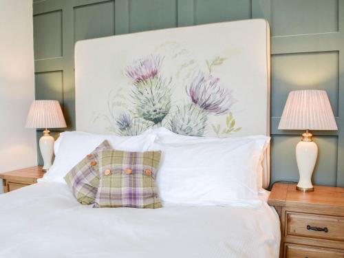 a bedroom with a white bed with two lamps at Bogrie Country Cottage in Canonbie