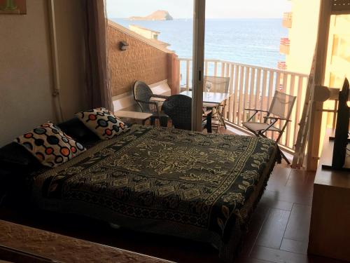 a bedroom with a bed and a balcony with the ocean at Apartamento Vistamar in La Manga del Mar Menor