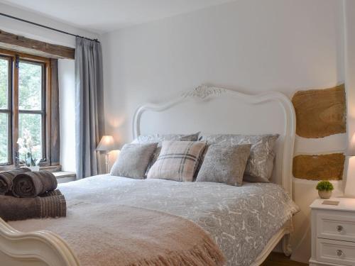 a white bedroom with a white bed with pillows at Gem Cottage in Longnor
