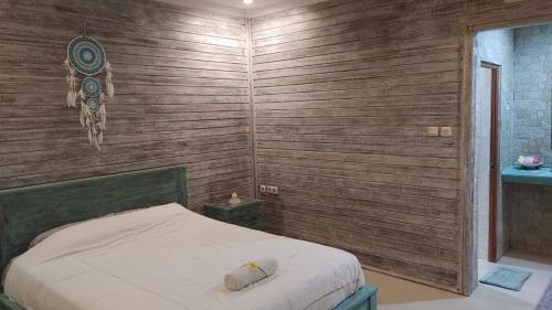 a bedroom with a bed in a wooden wall at Sarinah Beach - Bistro & Bungalow in Nusa Penida