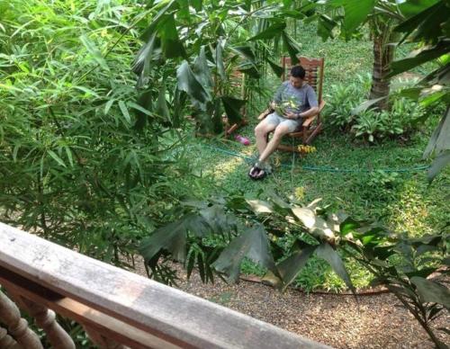 a person sitting in a chair in a garden at Sala Thongyon - Guest House in Savannakhet