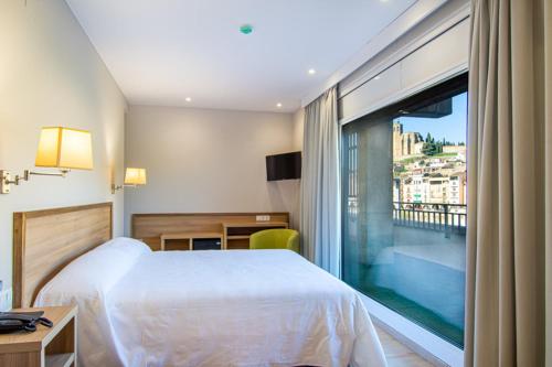 Habitación de hotel con cama y ventana grande en HOTEL JAUME D'URGELL, en Balaguer