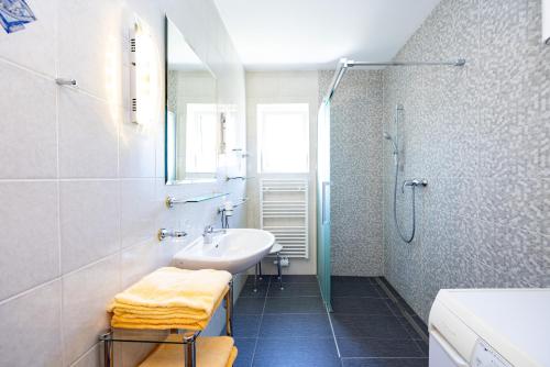 ein weißes Bad mit einem Waschbecken und einer Dusche in der Unterkunft Appartements Walzl in Maria Lankowitz