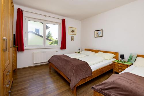 a bedroom with two beds and a window with red curtains at Appartmenthaus Köflach in Köflach