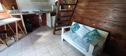 ein Zimmer mit einem Sofa und einer Küche mit einem Waschbecken in der Unterkunft Les Cabanes du Voyageur in Sainte-Marie