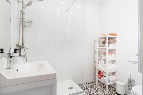a bathroom with a sink and a shelf with towels at Lovely 2 Bedroom Apartment in Caparica in Almada