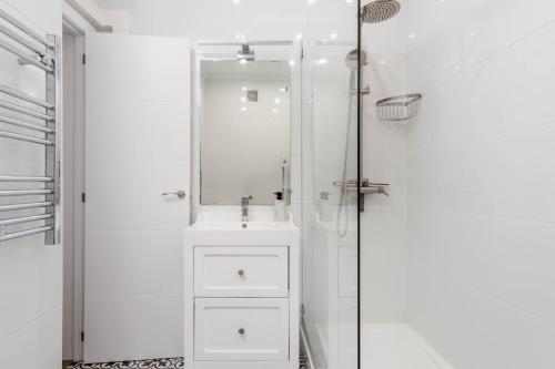a white bathroom with a sink and a shower at Lovely 2 Bedroom Apartment in Caparica in Almada