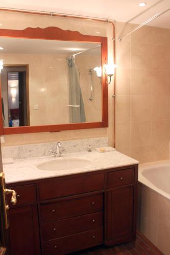 une salle de bain avec un lavabo, une baignoire et un miroir dans l'établissement Appartement La Belle View, à Annecy