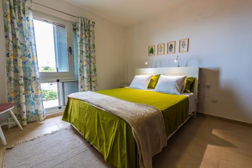 una camera da letto con un letto con una coperta verde e una finestra di Casa Los Mangos - Increíbles vistas a Playa de Santiago
