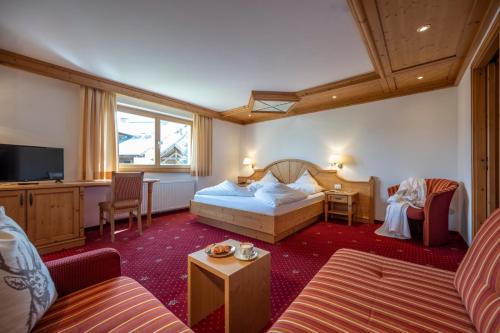 Habitación de hotel con cama y sala de estar. en Hotel Bellavista, en Alpe di Siusi