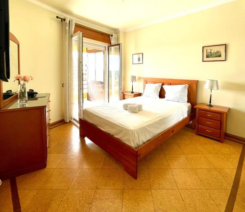 een slaapkamer met een groot bed en een balkon bij Cosy Sea View Apartment in Costa da Caparica