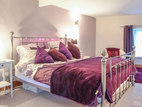 a bedroom with a bed with purple sheets and pillows at Mallams in Castletown