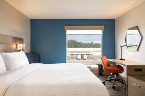 a hotel room with a bed and a desk and a window at Holiday Inn Express & Suites Opelousas by IHG in Opelousas