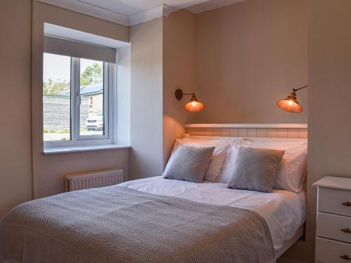 1 dormitorio con 1 cama con 2 almohadas y ventana en Swallow Cottage, en Gowerton