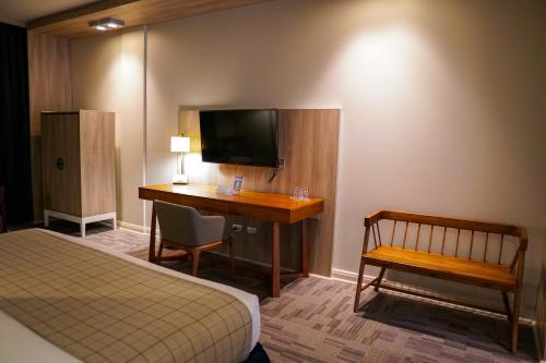 a hotel room with a desk and a bed and a television at Hotel Parada Linares in Linares