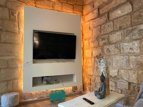 sala de estar con pared de piedra y TV de pantalla plana. en Moi, en Birkirkara
