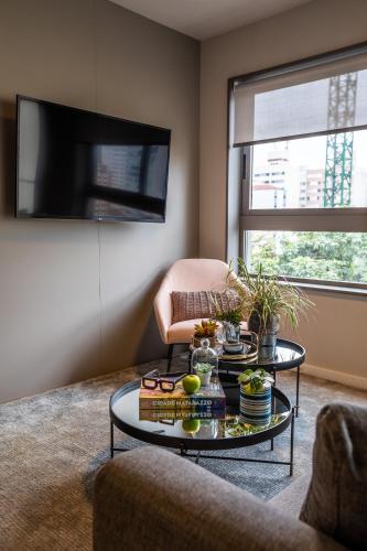a living room with a coffee table and a tv at Noon Vila Madalena in Sao Paulo