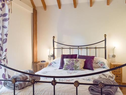 a bedroom with a wrought iron bed with purple pillows at The Cotes in Malvern Wells