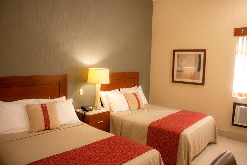 una habitación de hotel con 2 camas y una lámpara en Hotel Fenix, en Los Mochis
