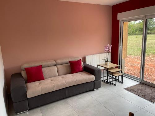 ein Wohnzimmer mit einem Sofa mit zwei roten Kissen in der Unterkunft Gite d Annie et J-louis 