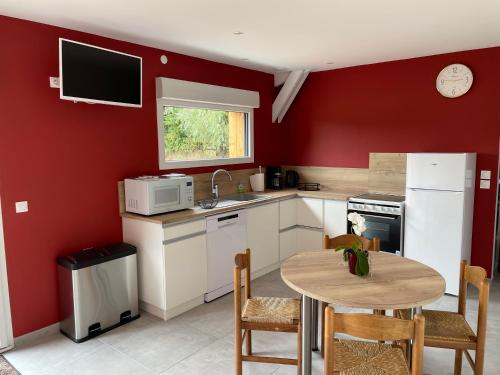 una cocina con paredes rojas y una mesa pequeña con sillas. en Gite d Annie et J-louis, 