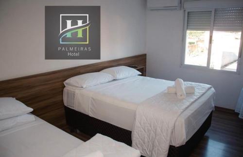 a hotel room with two beds with white sheets at Hotel Palmeiras in Santana do Livramento
