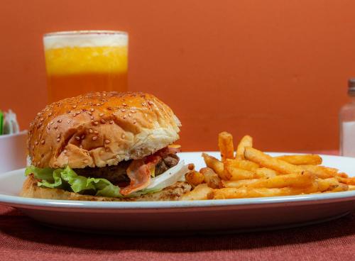 a plate with a sandwich and french fries and a glass of orange juice at Hotel Fenix in Los Mochis