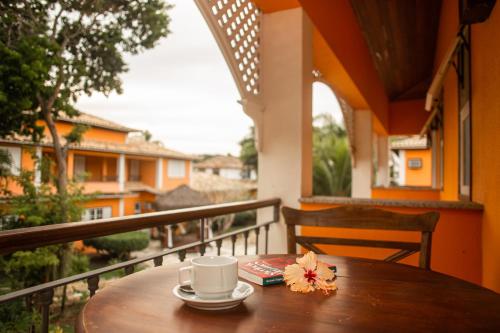 a wooden table with a coffee cup and books on a balcony at Pousada Corsario Buzios in Búzios