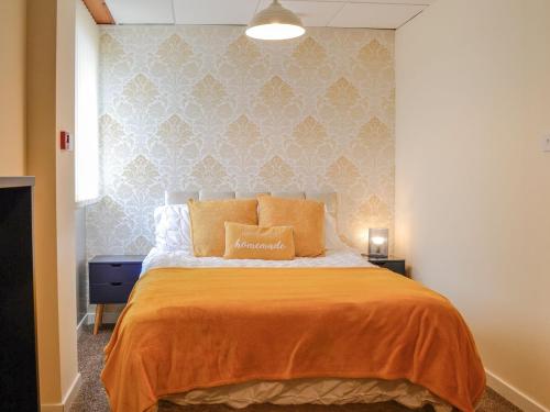 a bedroom with a large bed with an orange blanket at 1 Ladyknowe - Uk39970 in Moffat