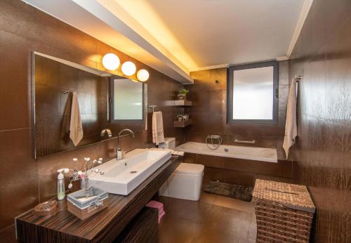 Optasia Luxury House في أرغوس: حمام مع حوض كبير ومغسلة