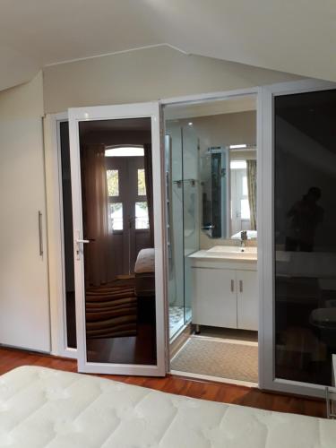 Łazienka z przesuwnymi szklanymi drzwiami i umywalką w obiekcie CARIBBEAN POOL-SIDE VILLA 1148 w mieście Port Edward