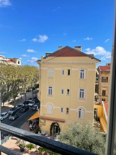 um edifício amarelo numa rua com estacionamento em MENTON STUDIO FACE AU JARDIN BIOVES FÊTES DES CITRONS 3min DE LA MER em Menton