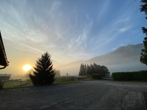 an empty road with the sun setting in the distance at Pension Dorferwirt in Bramberg am Wildkogel