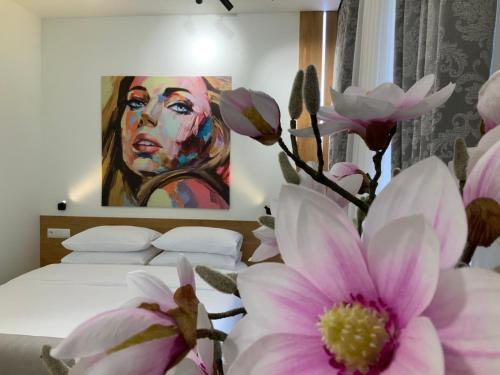 a bedroom with a painting of a woman with pink flowers at Apartment z kominkiem w sercu Wrocławia in Wrocław