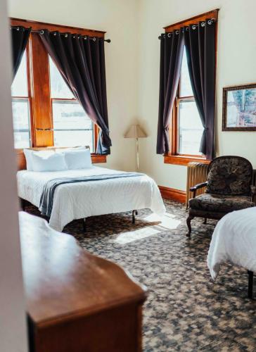 a bedroom with two beds and a chair and windows at Town Hall Inn in Lead