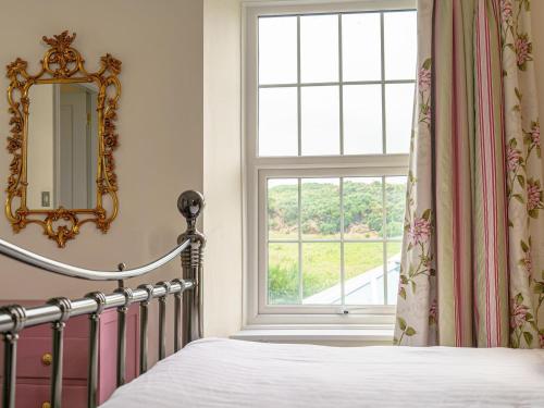 1 dormitorio con cama con espejo y ventana en Y Graiglwyd, en Amlwch