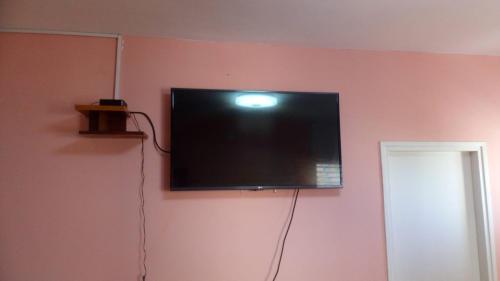 a flat screen tv hanging on a pink wall at Private room in the сomfortable apartment in Ashdod, 7 min walk to the beach in Ashdod