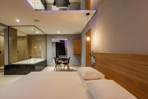 ein Schlafzimmer mit 2 Betten und ein Badezimmer mit einer Badewanne in der Unterkunft Drops Express Motel in Barretos