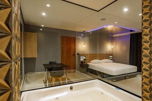 Drops Express Motel في باريتوس: حوض استحمام في غرفة مع سرير