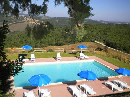 una piscina con ombrelloni blu e sedie a sdraio di Monte Fugnano a Gubbio