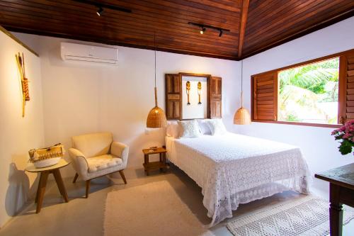 a bedroom with a bed and a chair and a window at Casa João Viera Trancoso in Trancoso