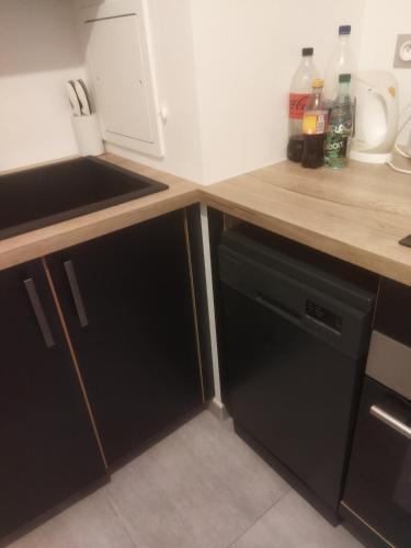 - une cuisine avec des armoires noires et un lave-vaisselle noir dans l'établissement Appartement neuf T2 dans résidence, à Schiltigheim