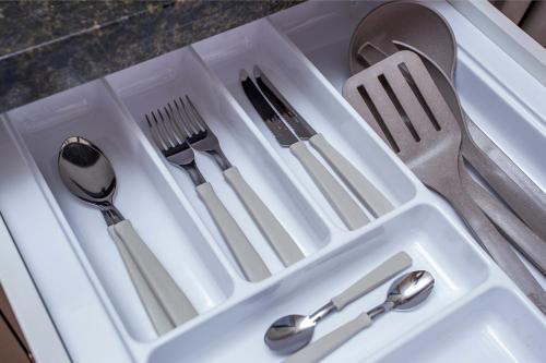a white tray with silver utensils in a sink at GoÁtica Aeroporto Congonhas in Sao Paulo