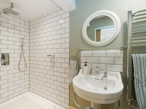 a white bathroom with a sink and a mirror at Mortimer Trail Mews in Aymestrey