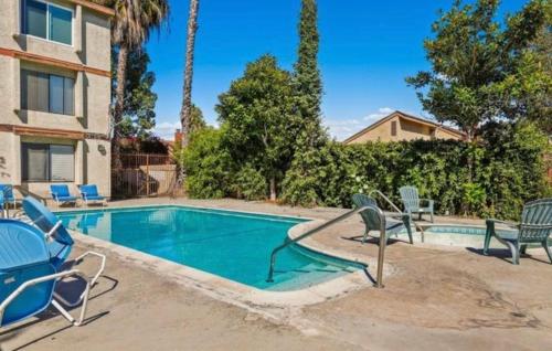a swimming pool with chaise lounge chairs next to a house at Condo Near LAX & Sofi in Los Angeles