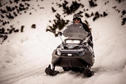 a person riding a snowmobile in the snow at Horsky Hotel Sliezsky Dom in Vysoké Tatry