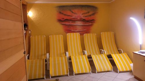 a group of yellow chairs in a room with a painting at Knaller der Reiterbauernhof in Reisach