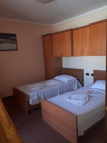 two beds in a room with wooden cabinets at Hotel Meteor in Shkodër