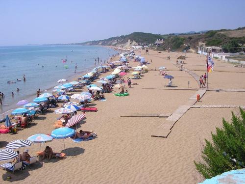 a group of people on a beach with umbrellas at Santa Barbara Lakis Apartments in Perivolion