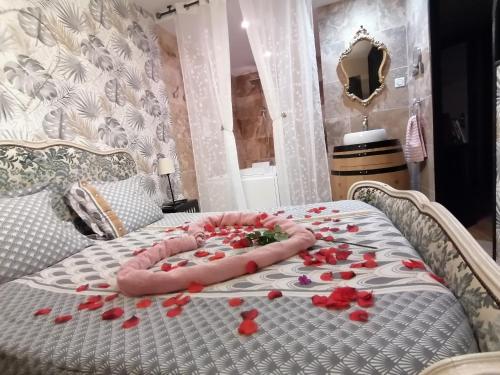 a bed with red rose petals on it at Romantisme et glamour avec spa, piscine et jardin in Dijon